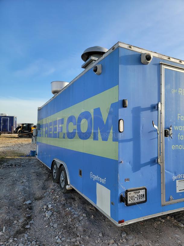 Blue mobile kitchen trailer with ventilation units, Texas license plate, and "@getreef" branding; scratches visible.