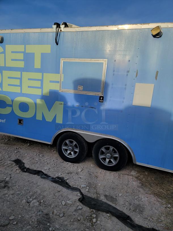 Blue food trailer with "GET BEEF" text, double axle, service window, security camera. Some exterior wear visible.