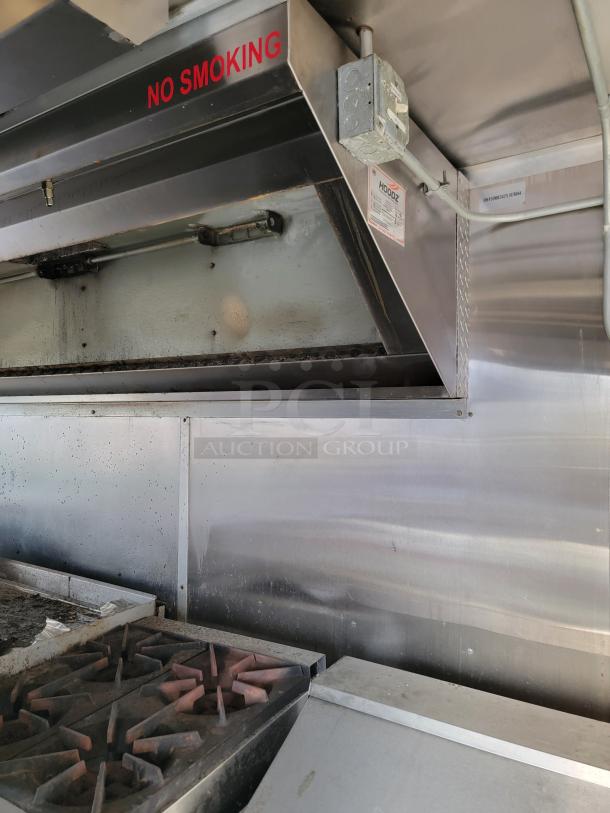 Commercial kitchen range hood with a "No Smoking" sign, stainless steel finish, and visible wiring. Signs of use present.