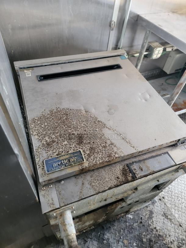 Arctic Air commercial refrigerator, shows significant rust and wear. Metal label indicates brand. Needs restoration.