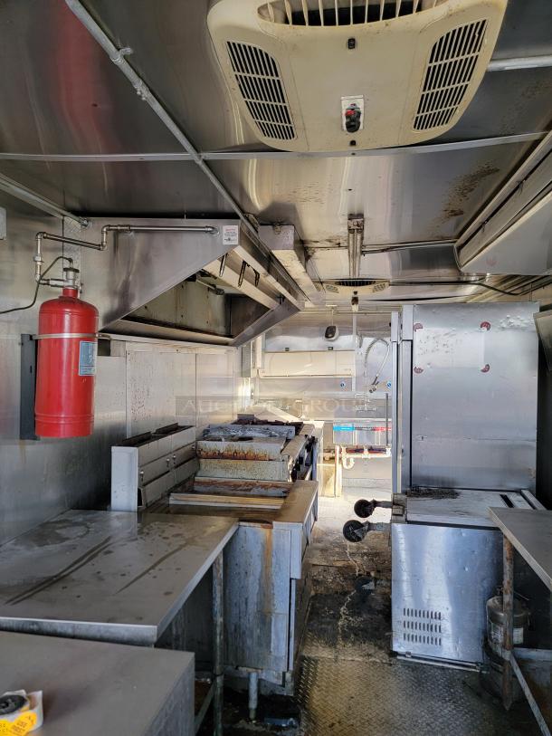 Commercial mobile kitchen interior with stainless steel surfaces, ventilation hood, fire extinguisher, and cooking equipment. Used condition.
