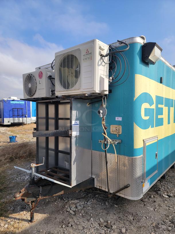 Large outdoor trailer with LG and Mirage VentusX air conditioning units. Blue and yellow exterior. Signs of outdoor wear.