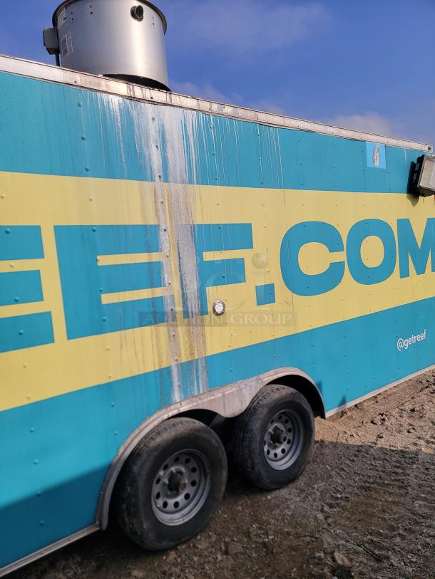 Blue and yellow food truck with dual axles, visible logo "@getreef", exterior wear and stains, rooftop vent.