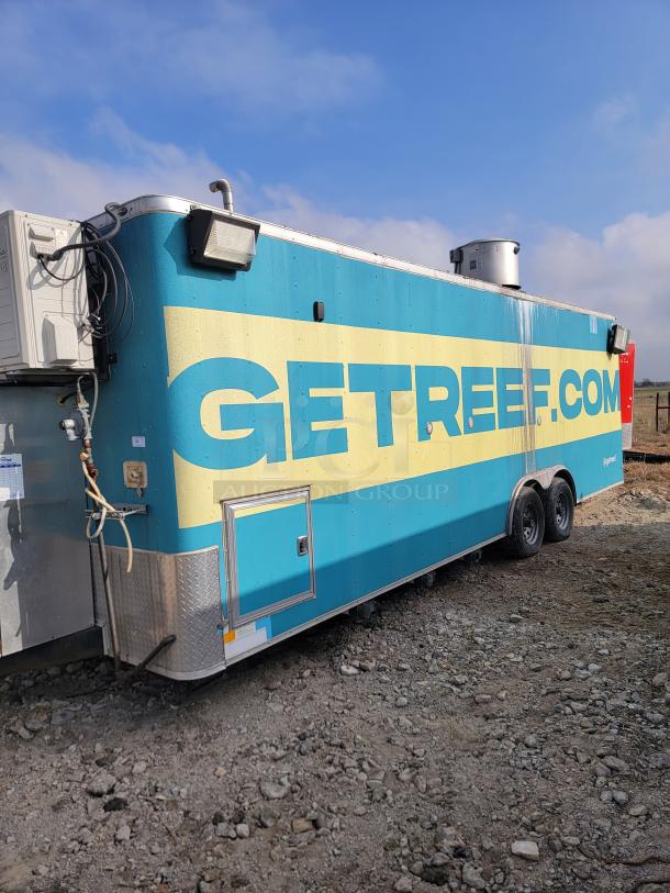Mobile kitchen trailer with "GETREEF.COM" branding, tow hitch, vents, and air conditioning unit. Blue and yellow exterior, dual axles.