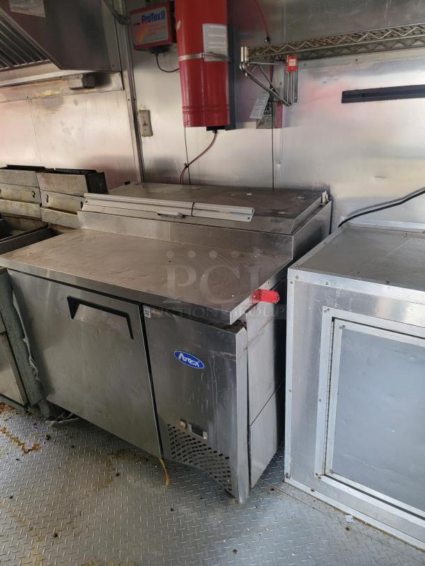 Commercial stainless steel prep table with Arctic branding, under-counter storage, and visible wear. Ideal for food service use.