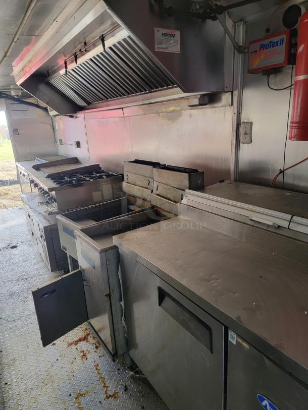 Commercial kitchen equipment, including stainless steel countertop, stove, and deep fryers. Visible wear on surfaces. Hoodz and ProTex II signage present.
