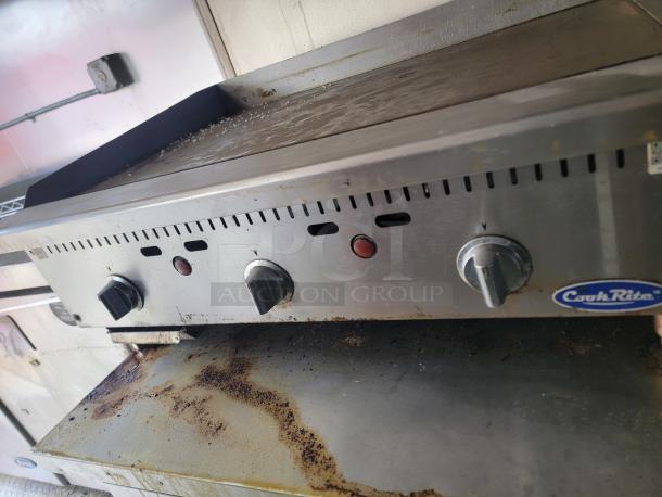 CookRite griddle with three control knobs, stainless steel, used condition, visible grease stains, logo on front.