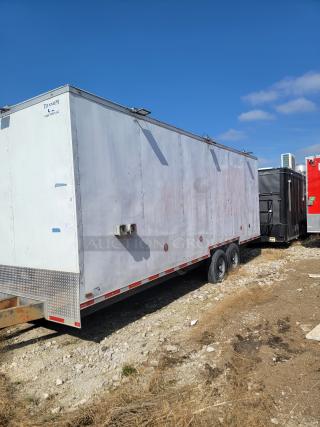 White Titanium cargo trailer with dual axles, side vents, visible wear, and wear on the exterior. Marked "Titanium Cargo Trailers LLC."