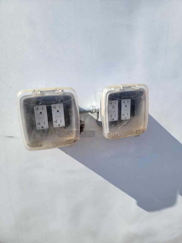 Outdoor electrical outlets with protective covers, mounted on a wall. Some wear visible on covers.