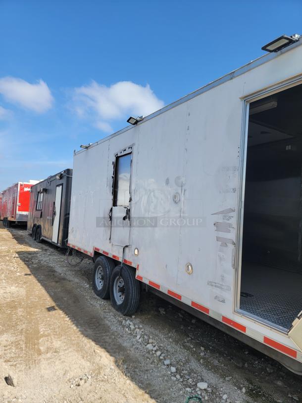 Large white trailer with twin axles, visible side damage, and missing door. Dented exterior suggests need for repair.