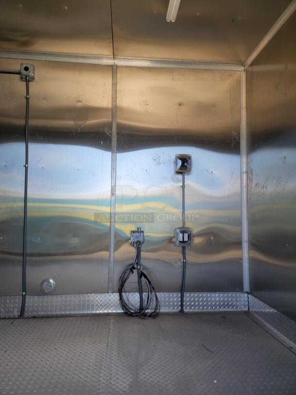 Interior of a metal-walled trailer with electrical wiring and outlets, diamond plate flooring. Good condition, ready for use.