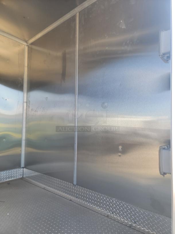 Interior view of a metal storage container or trailer. Features smooth, shiny walls and diamond plate flooring. Slight wall dents visible.