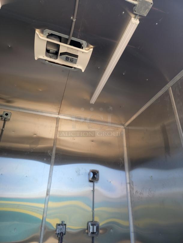 Interior of a metallic enclosure with ceiling-mounted equipment, fluorescent light, and electrical wiring. Appears in good condition.