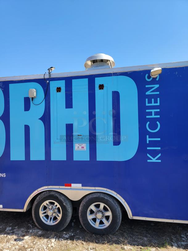 Blue kitchen trailer with dual axles, large "BRHD" text, visible vent, and utility connections. Appears in good condition.
