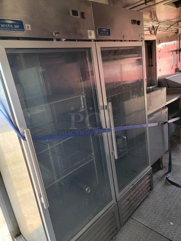 Arctic Air commercial refrigerator, double glass doors, metal handles, used condition. Labels and temperature controls visible.