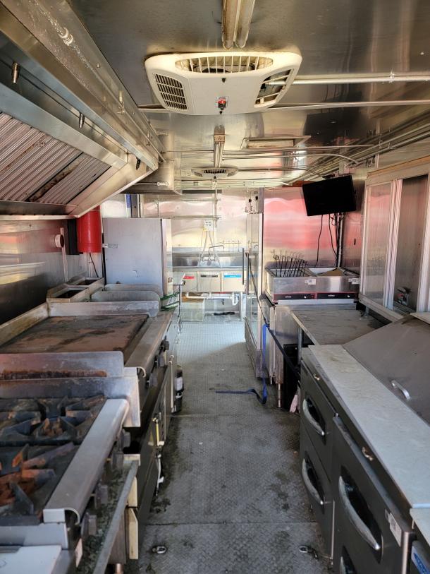 Mobile kitchen interior with industrial equipment, including ovens, grills, and ventilation system. Used condition, clean layout.