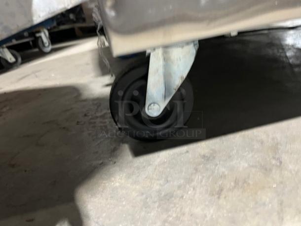 True TRCB-52-60 stainless steel refrigerated chef base corner with caster, showing mobility feature.