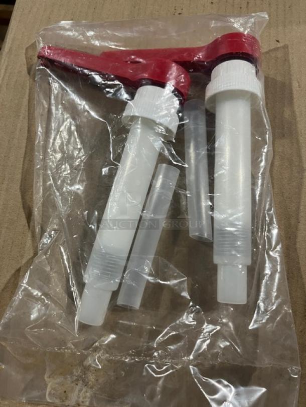 Brand new commercial condiment dispenser pump with red top, sealed in plastic packaging.