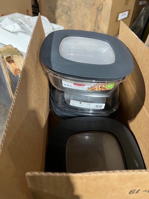 Brand new commercial Rubbermaid Brute lids and clear food storage containers in a box. Labels visible on packaging.