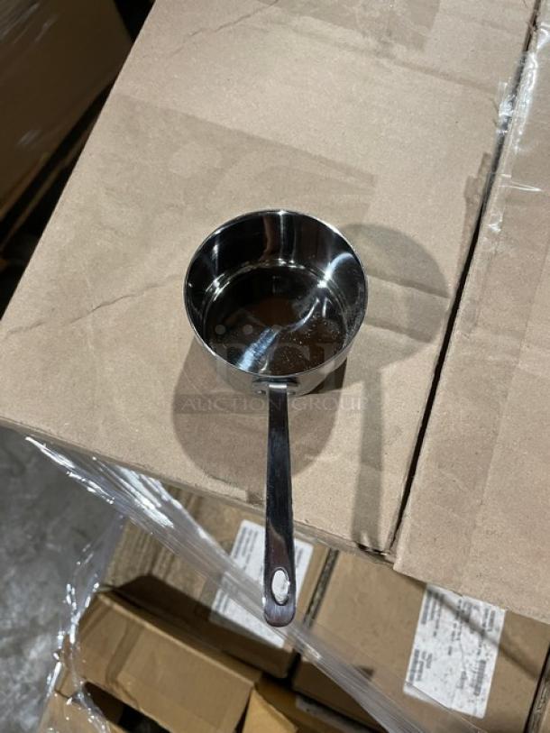Stainless steel 2.75" presentation pan, model F91019, on top of a cardboard box, part of a mixed commercial kitchenware pallet.