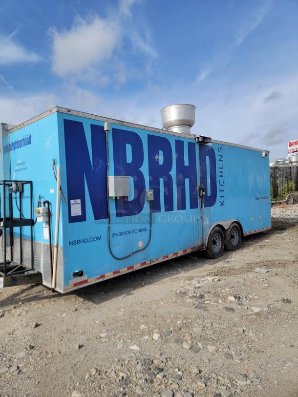 Large blue food trailer with "NBRHD KITCHENS" branding, multiple hatches, exhaust vent on top, and visible wear.