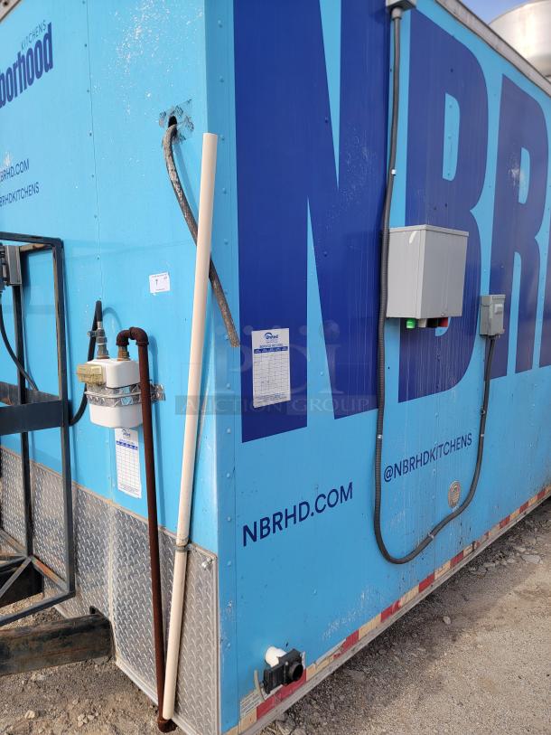 Blue food truck with "NBRHD KITCHENS" branding, electrical boxes, and labels; appears used with visible wear.