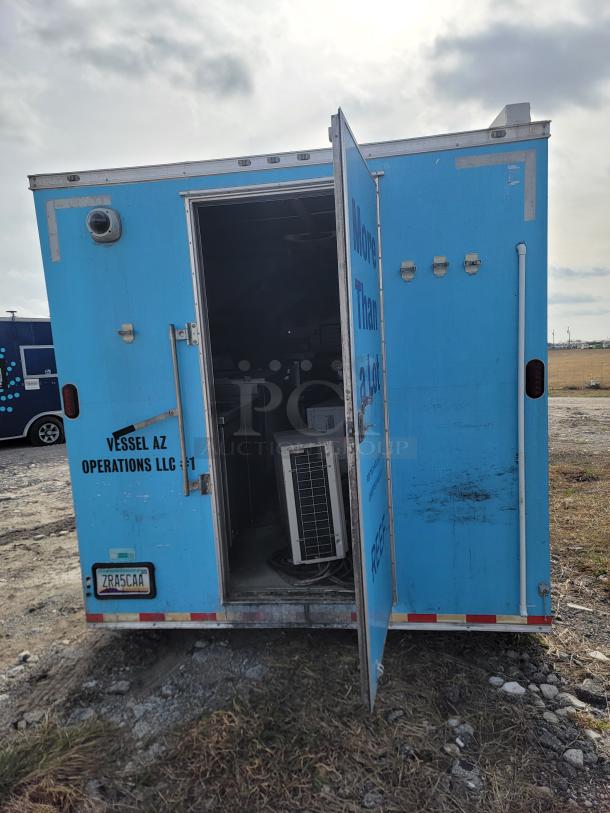 Blue utility trailer with open door, revealing interior equipment. Markings include "Vessel AZ Operations LLC" and a visible license plate.