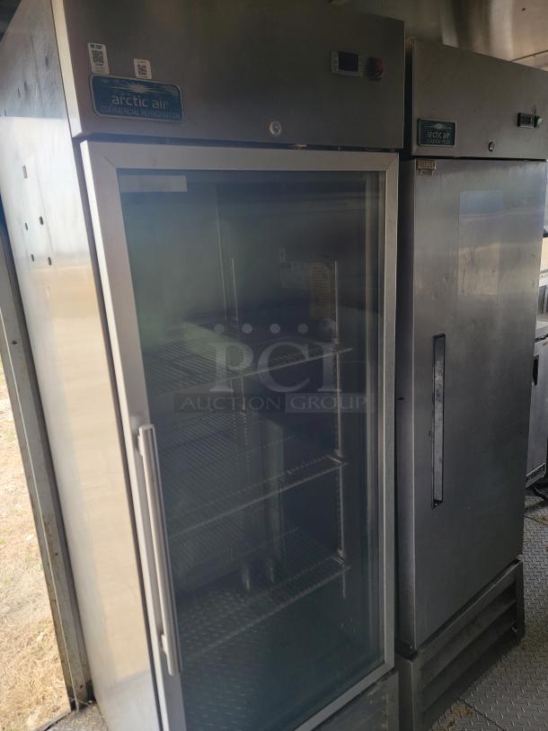 Arctic Air commercial refrigerator, glass door, stainless steel, multiple shelves, good condition, brand labels visible.