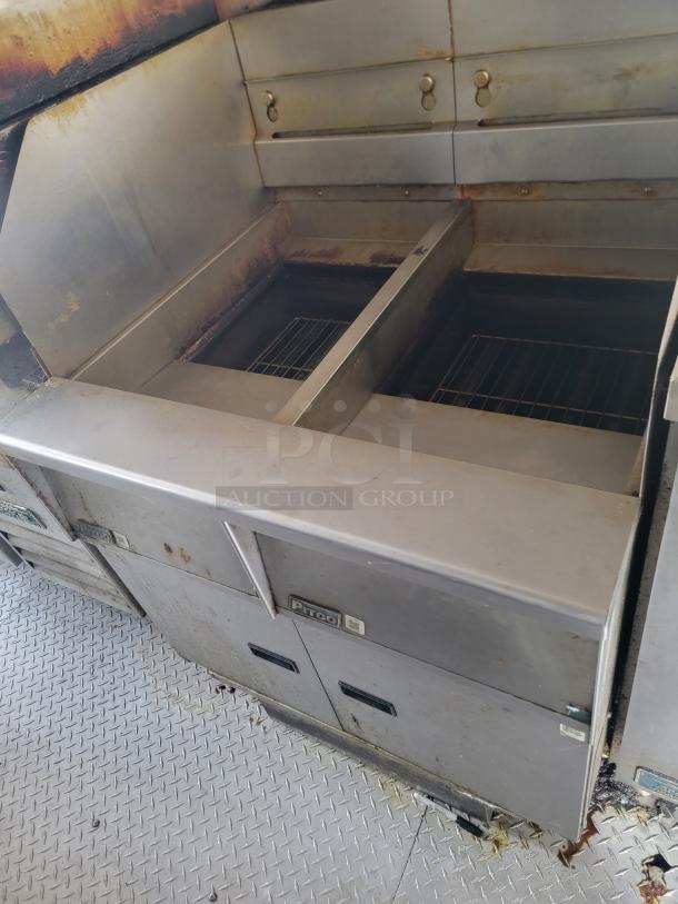 Pirco stainless steel commercial grill with dual compartments. Visible wear and rust; includes control knobs and branding.