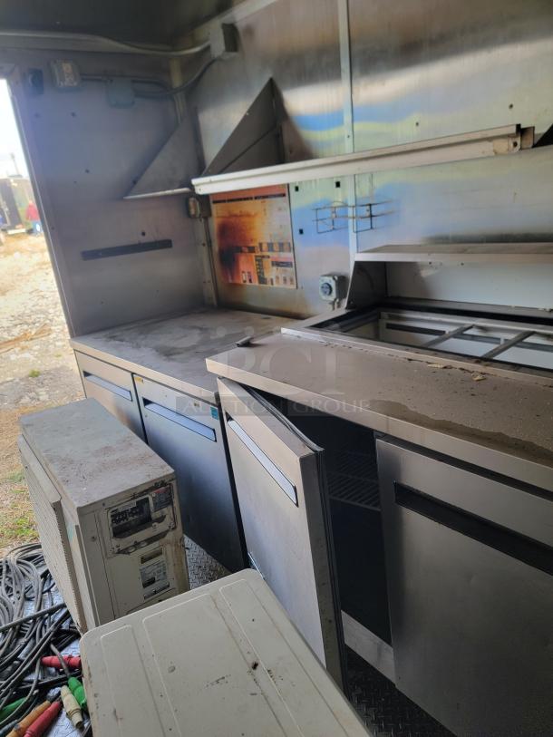 Commercial kitchen equipment, stainless steel counters with storage and refrigeration units. Good condition, slight wear.