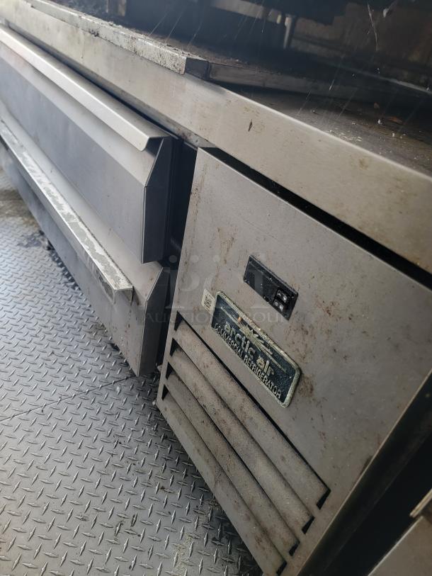 True Refrigeration commercial refrigerator, used condition, with visible wear. Features dual doors and metallic finish. Visible label indicates model details.