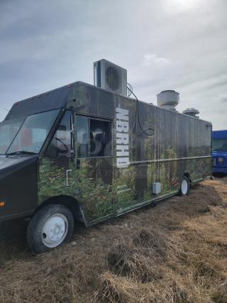 Food truck with forest-themed wrap, featuring "NBRHD Kitchens" text. Mitsubishi air conditioner on top, parked on grass.