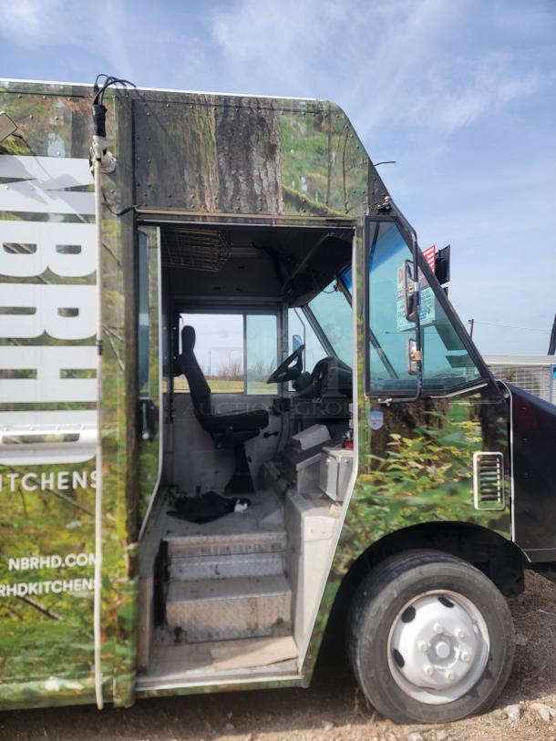 Camouflaged food truck with open driver door, interior seating visible. "NBRHD Kitchens" branding and website on exterior.