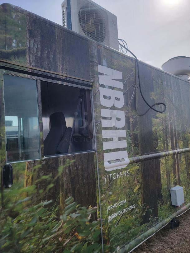 Auction item: Food truck with forest-themed wrap, NBRHD Kitchens branding, visible air conditioning unit, and website URLs.