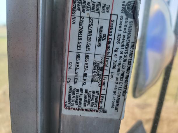 Close-up of vehicle tire information label showing tire size, pressure, seating capacity, and loading details, partially worn.