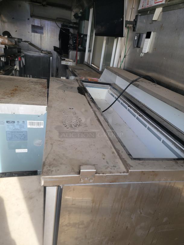 Stainless steel commercial kitchen appliance, lid open, showing internal storage. Exterior in worn condition with visible rust.