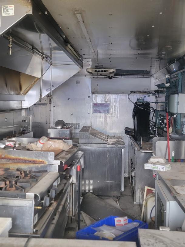 Commercial food truck kitchen with industrial appliances; includes stove, fryer, and prep areas. Moderate wear visible.