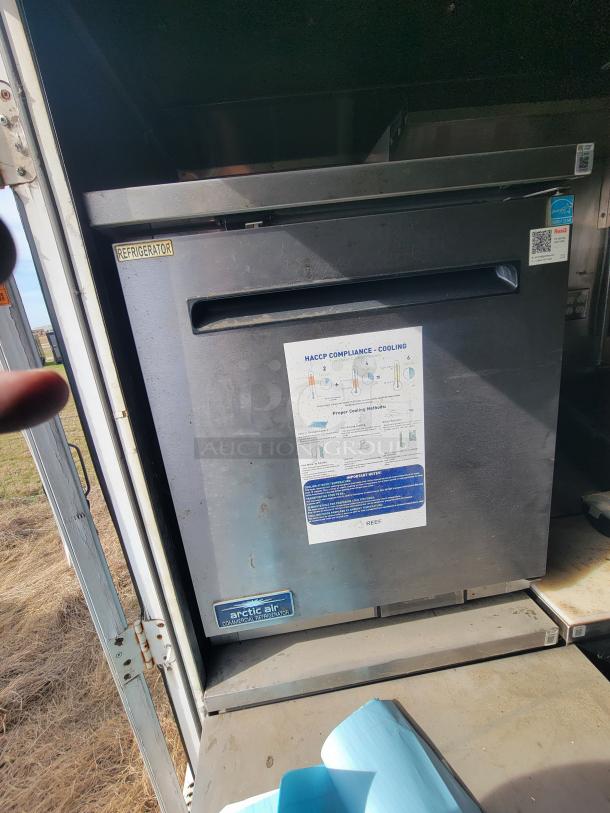 Arctic Air commercial refrigerator, silver, in used condition. Features cooling compliance label and visible brand logo.