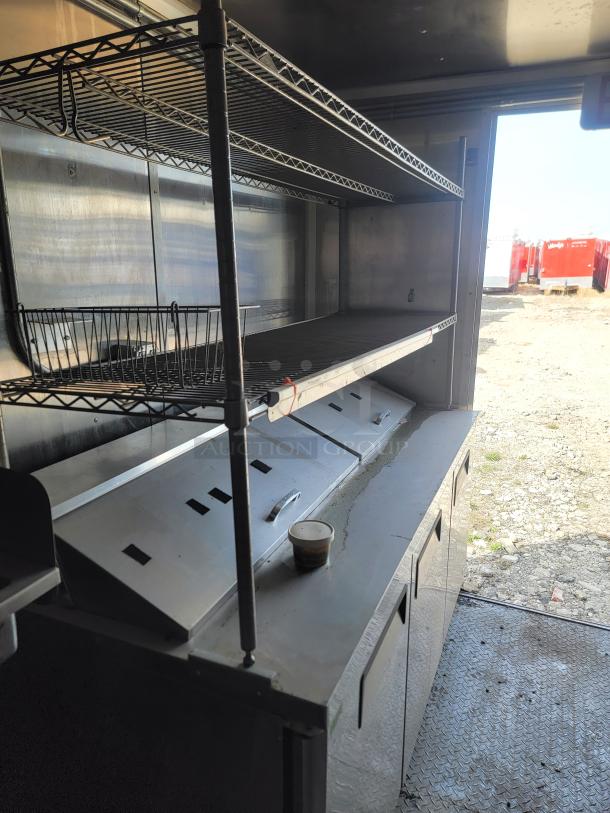 Commercial kitchen equipment featuring stainless steel shelving and countertop, equipped with multiple storage compartments.