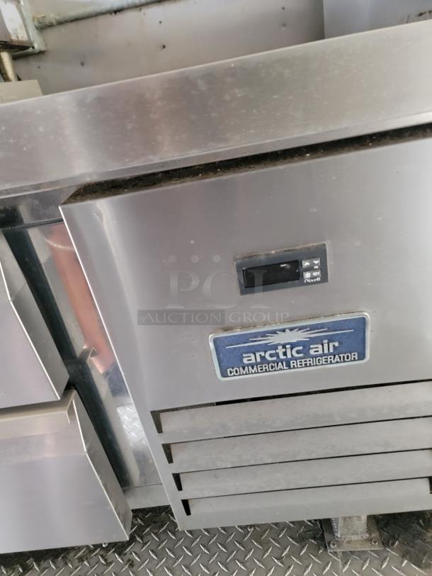 Arctic Air commercial refrigerator, stainless steel with digital display and logo, showing signs of wear.