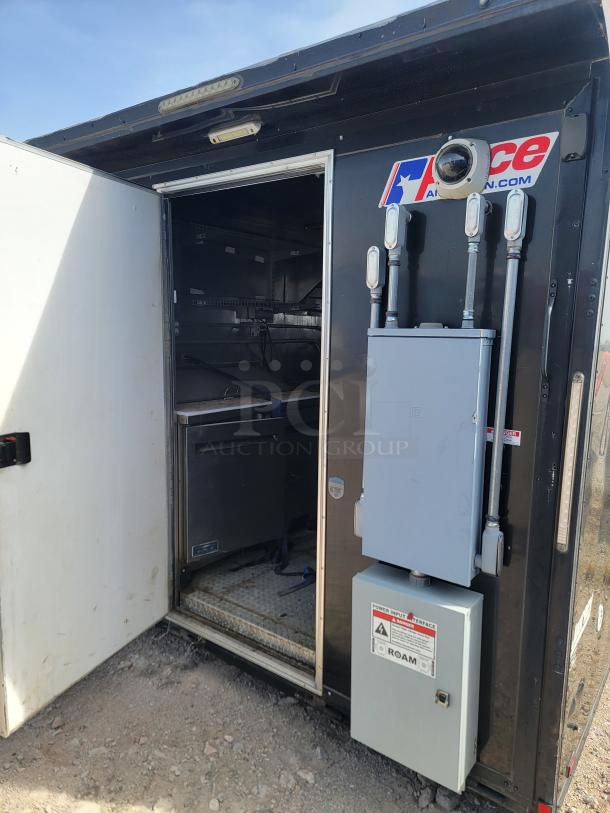 Mobile utility trailer with open door, electrical setup, AceAmerican.com logo, sturdy build, good condition, gravel background.