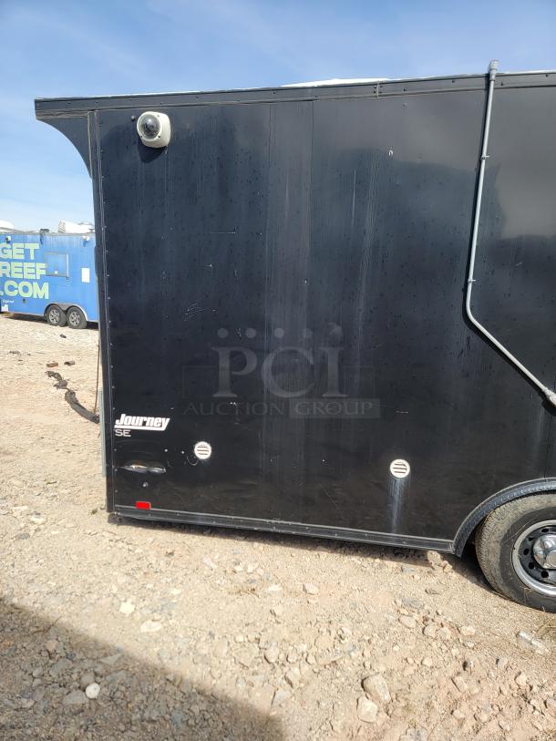 Black Journey SE trailer, fair condition, with mounted security camera and visible wheel; located outdoors.