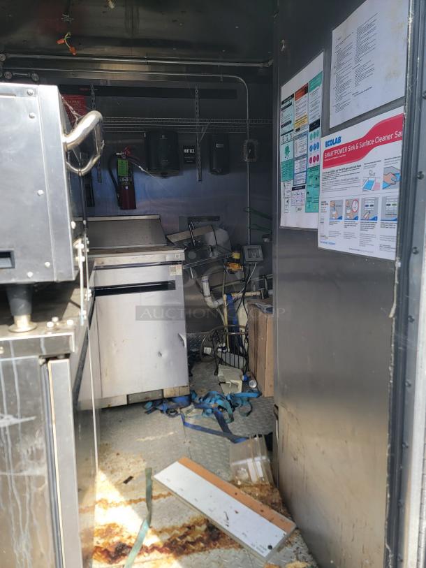Interior of a food truck with stainless steel equipment, fire extinguisher, and wall-mounted Ecolab sanitation instructions. Mixed conditions.