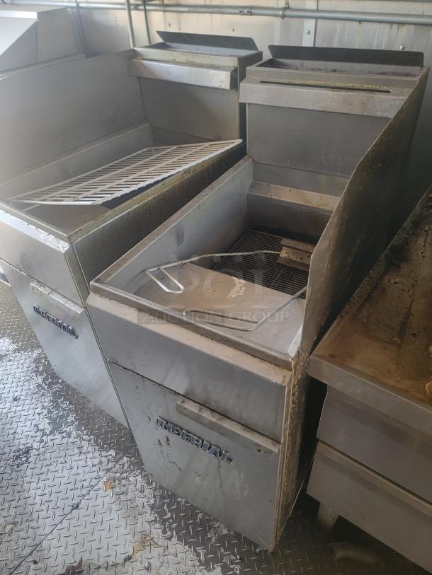 Commercial kitchen fryers by Imperial. Stainless steel construction, showing signs of use. Features dual compartments and wire rack.
