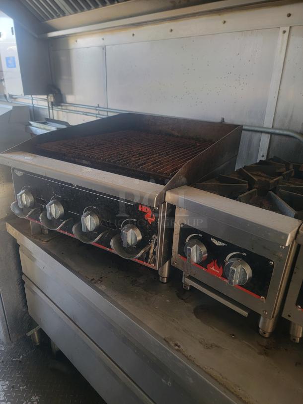 Commercial grill and stovetop combo with multiple control knobs, showing visible signs of use. Ideal for food service operations.