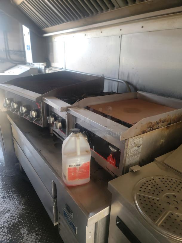 Commercial kitchen stove with multiple burners and griddle. Visible wear, includes Ecolab cleaning solution. Volcan brand logo shown.