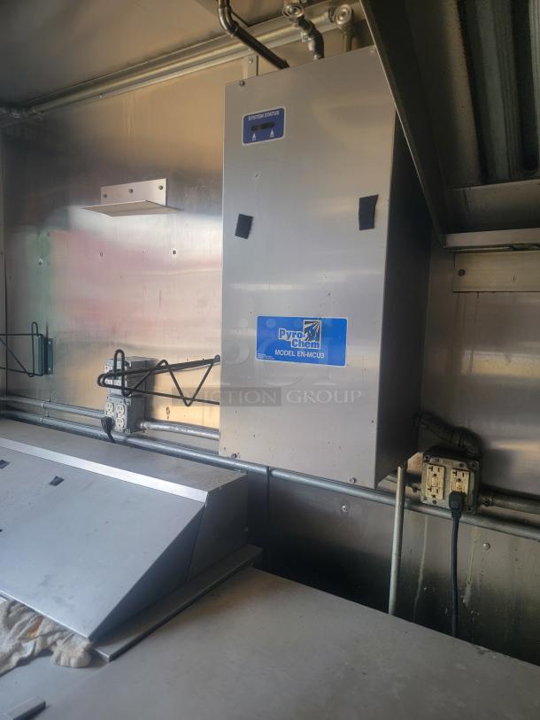 Pyro-Chem Model EN-MCU3, stainless steel fire suppression unit. Features system status indicator. Mounted in a commercial kitchen.