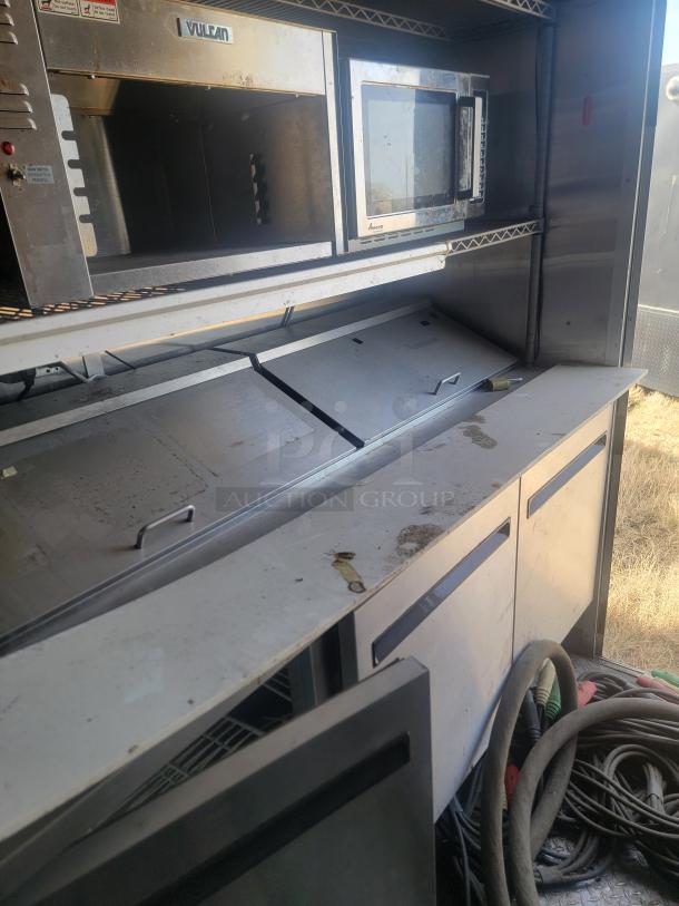 Commercial kitchen setup featuring a Vulcan convection oven and microwave, showing moderate wear and visible wiring below.