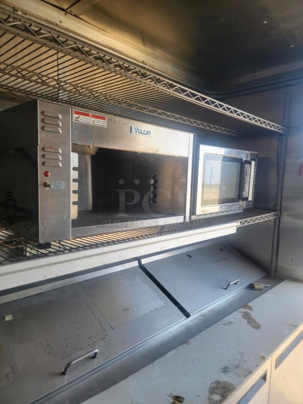 Vulcan stainless steel commercial oven, used, with visible wear. Features control panel, door handle, mounted on a metal shelf.