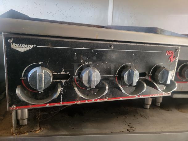 Vollrath commercial stove controls with HD branding. Features four knobs, showing wear. Adjusts from low to high heat settings.